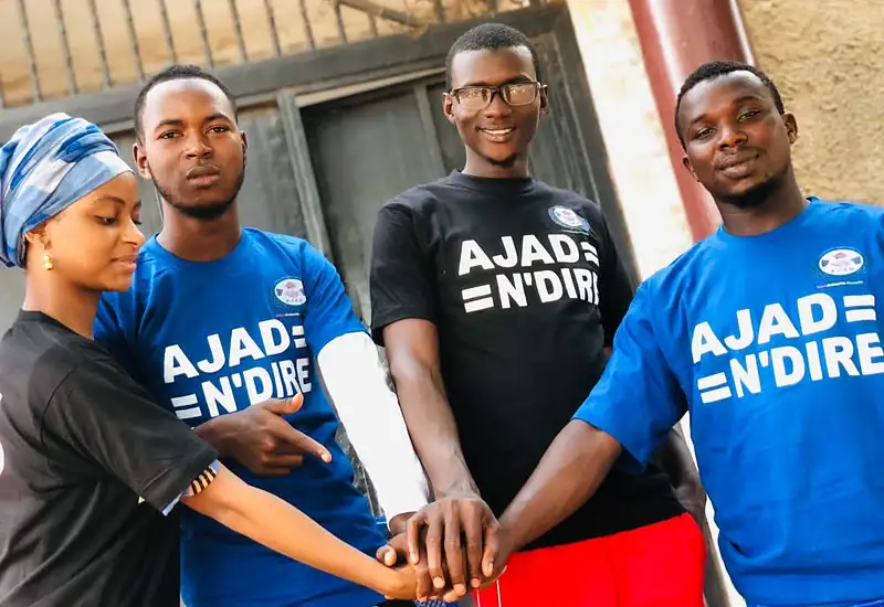 Quatre membres de l'AJAD en t-shirt AJAD N'Diré, les mains réunies